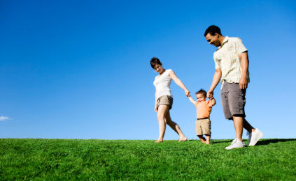 An image of parents walking their child in an open field